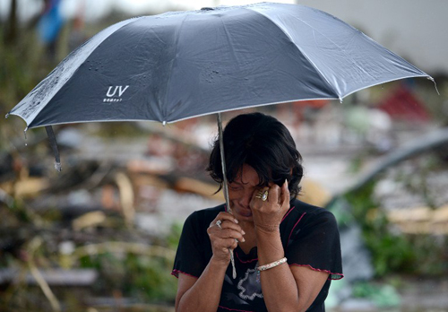 [Caption]A woman mourns in front of her husband's dead body in a street of Tacloban, eastern island of Leyte on November 10, 2013.