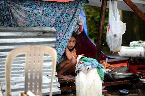[Caption]A girl peeks out from a makeshift shelter in Tacloban, on the eastern island of Leyte on November 10, 2013 after Super Typhoon Haiyan swept over the Philippines. 